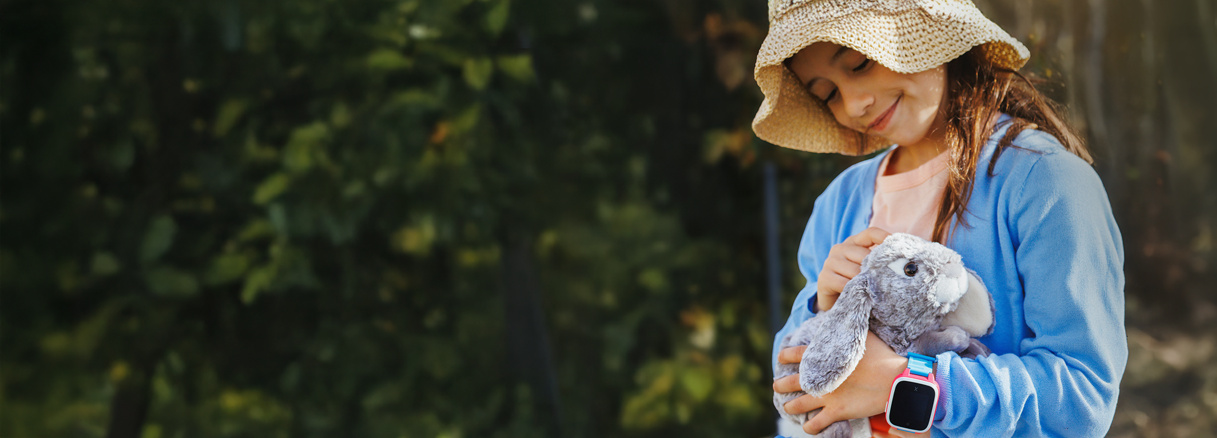 Child holding a stuffed animal with a blurred green background