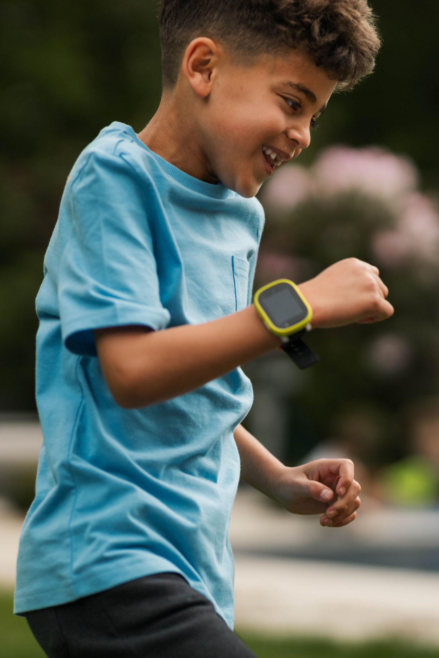 Boy running outdoors and looking at a Xplora smartwatch on his wrist